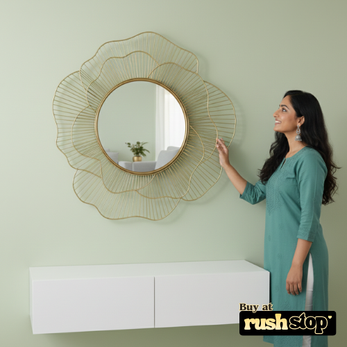 Woman pointing at a decorative wall mirror on a light green wall.