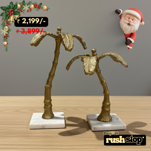 Decorative palm tree sculptures on marble bases with a Santa Claus figure in the background.
