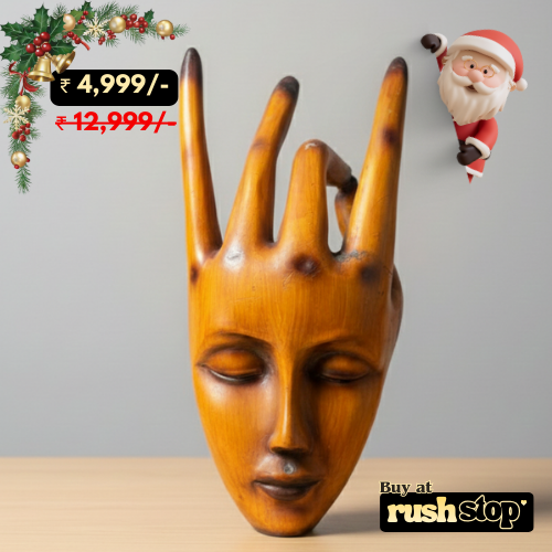 Wooden sculpture of a face with long fingers on a gray background, featuring Christmas decorations and a Santa Claus figure.