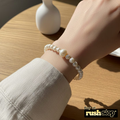 Artisan hand-knotted natural freshwater pearl bracelet featuring a prominent central Baroque pearl and gold-toned barrel clasp.