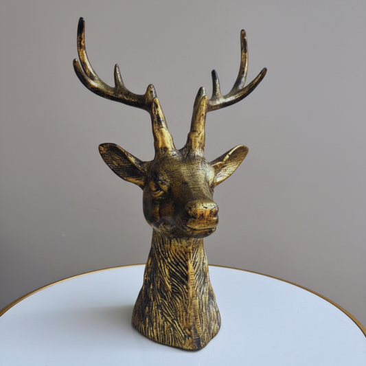 Bronze deer head sculpture on a white platform with a gray background