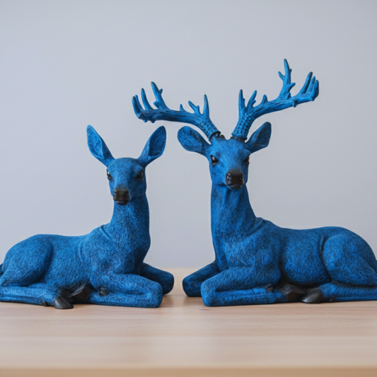 Two blue deer figurines on a wooden surface with a light gray background