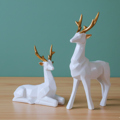 Two white deer figurines with gold antlers on a wooden surface and green background