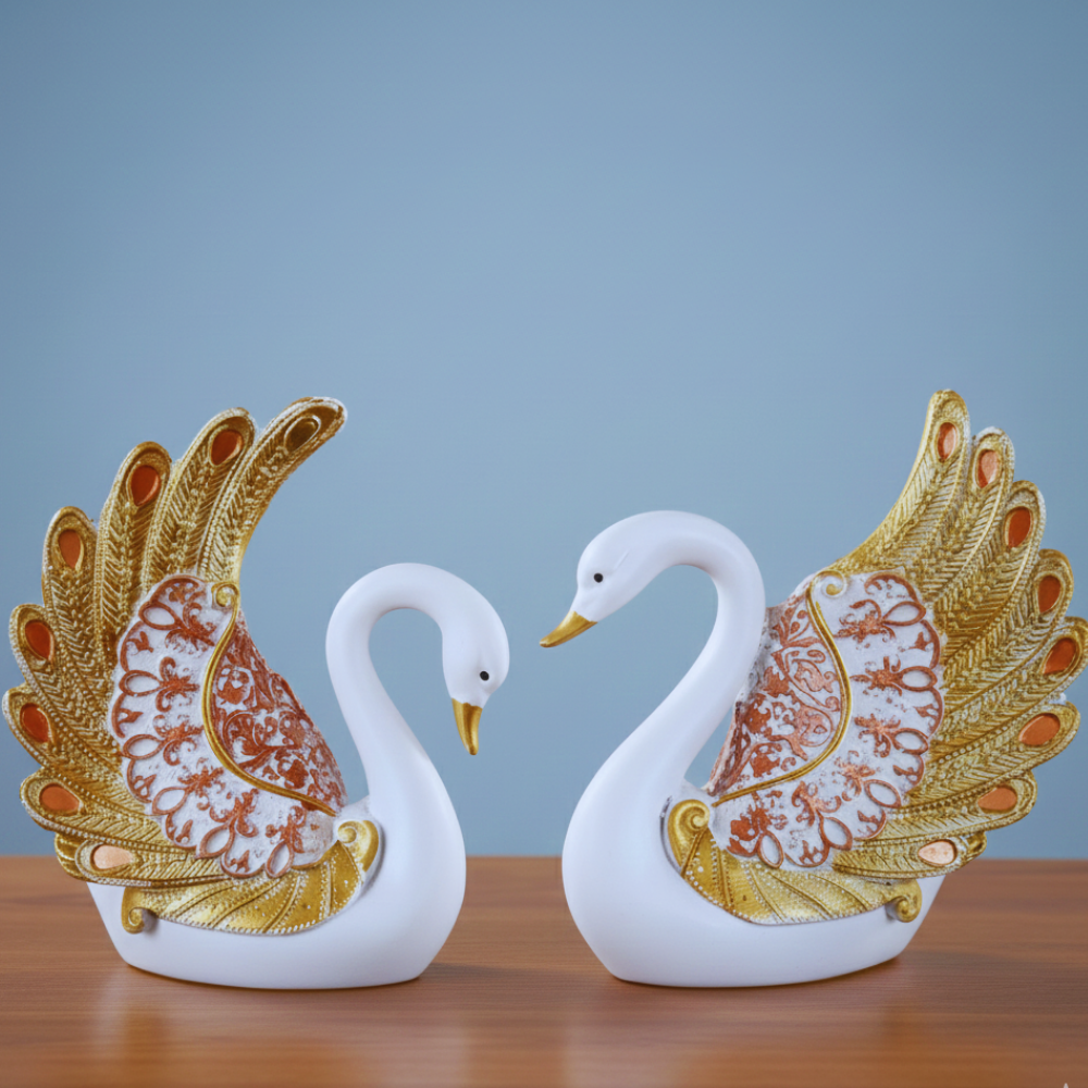 Two decorative swan figurines with gold and red details on a wooden surface and blue background