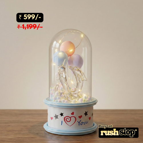 Decorative lamp with pastel balloons and LED lights inside a glass dome on a wooden surface.