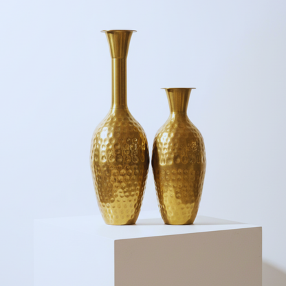 Two gold vases on a white pedestal against a light blue background