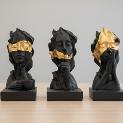 Three black figurines with gold masks on a gray background