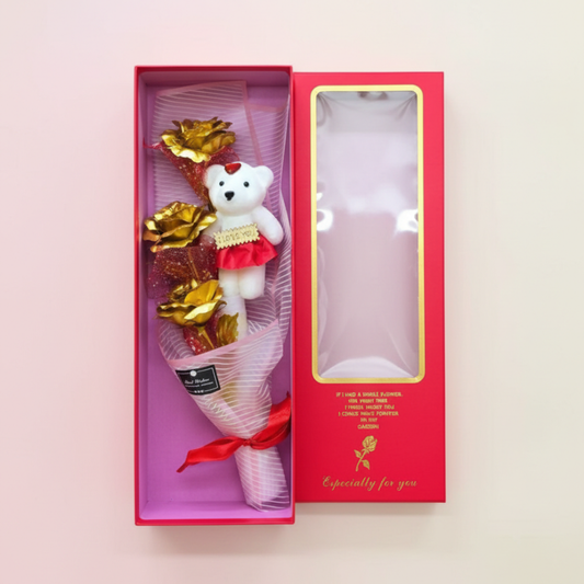 Bouquet with a teddy bear and gold leaves in a pink box on a light pink background