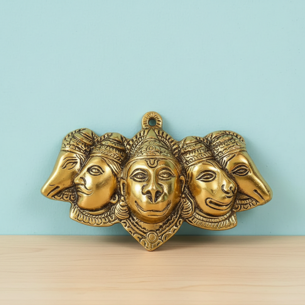 Gold-colored wall art with four faces on a light blue background