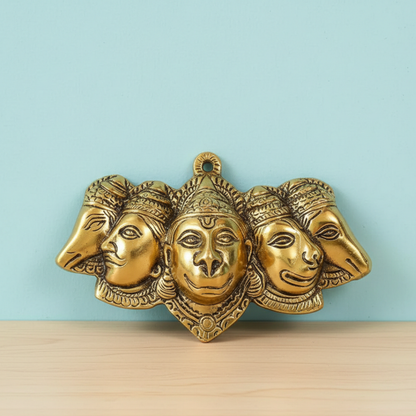 Gold-colored wall art with four faces on a light blue background