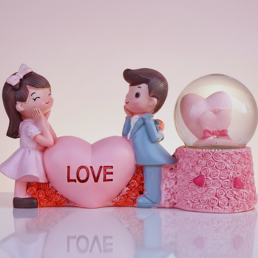 Decorative figurines of a girl and boy with a heart-shaped 'LOVE' sign on a light pink background.