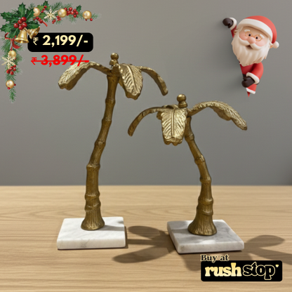 Decorative palm tree sculptures on marble bases with a Santa Claus figure in the background.